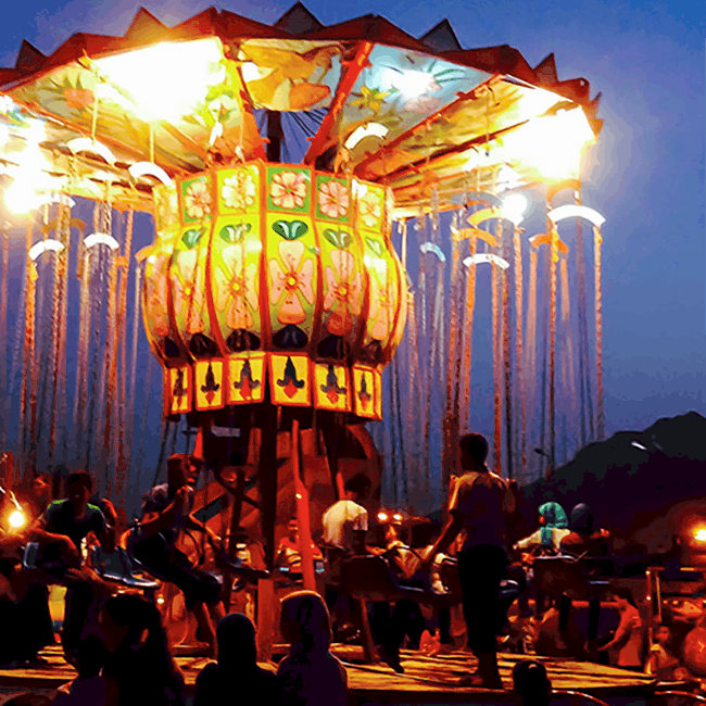 Image shows a brightly lit carnival ride full of Egyptian carnivalgoers.