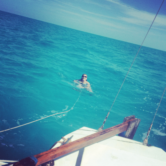 Image shows Jezebel smiling in the middle of the ocean. She is tied to the back of the boat with a rope.